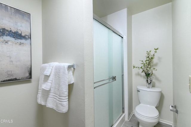 bathroom featuring toilet and an enclosed shower