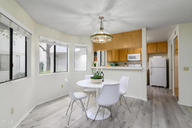 dining area with a textured ceiling and light wood-type flooring