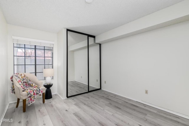 unfurnished room featuring light hardwood / wood-style flooring and a textured ceiling