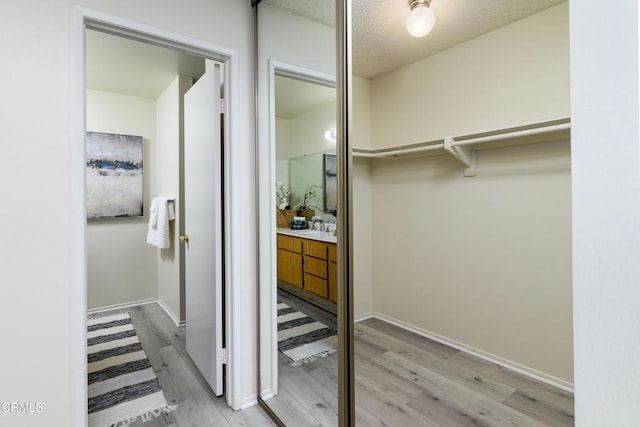 spacious closet featuring sink and light hardwood / wood-style flooring