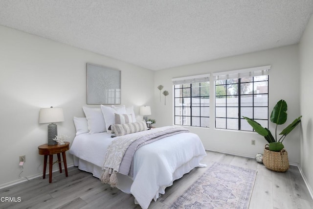 bedroom with a textured ceiling and light wood-type flooring