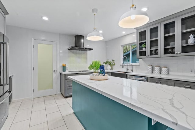 kitchen with gray cabinets, sink, wall chimney range hood, and decorative light fixtures