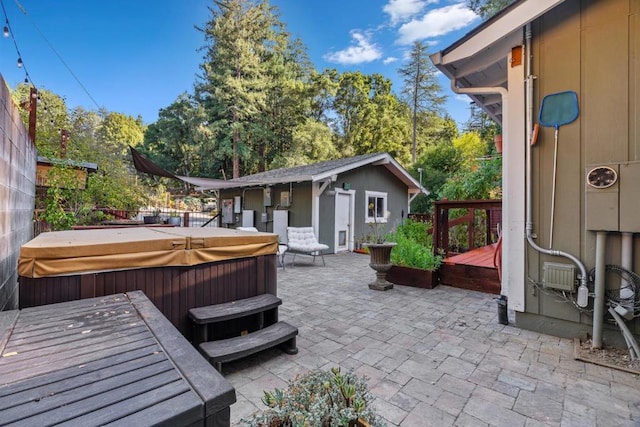 view of patio / terrace with an outbuilding, a hot tub, and a deck