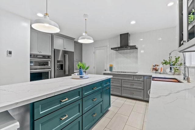 kitchen featuring hanging light fixtures, decorative backsplash, wall chimney exhaust hood, and appliances with stainless steel finishes