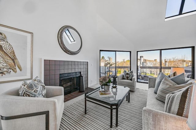 living room with a tiled fireplace and high vaulted ceiling