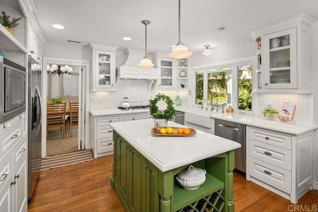 kitchen featuring appliances with stainless steel finishes, white cabinetry, hanging light fixtures, green cabinetry, and a kitchen island