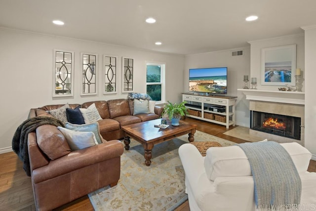 living room with ornamental molding, hardwood / wood-style floors, and a tile fireplace