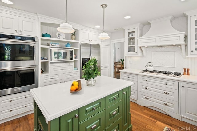 kitchen with a kitchen island, appliances with stainless steel finishes, white cabinetry, custom exhaust hood, and green cabinetry