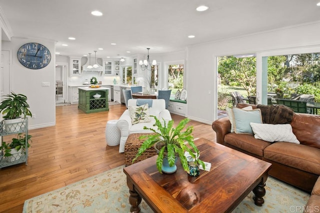 living room featuring ornamental molding, an inviting chandelier, and light hardwood / wood-style floors