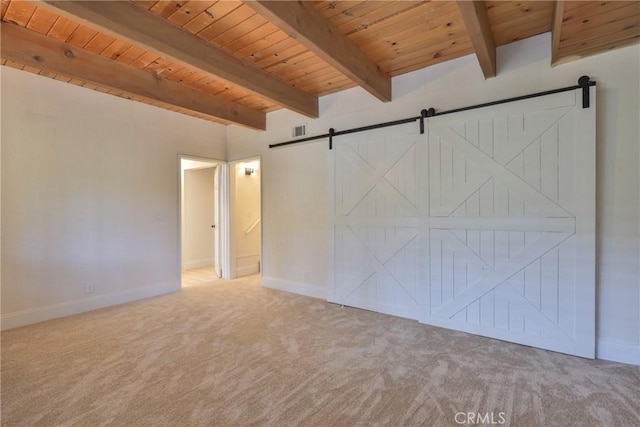 carpeted empty room with beamed ceiling, a barn door, and wooden ceiling