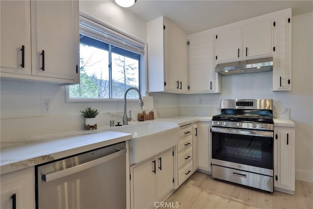 kitchen featuring sink, light wood-type flooring, white cabinets, and appliances with stainless steel finishes