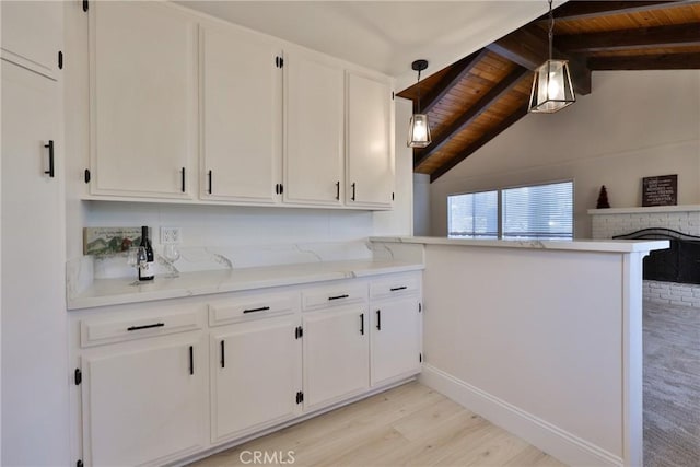 kitchen with hanging light fixtures, wooden ceiling, light wood-type flooring, kitchen peninsula, and white cabinets