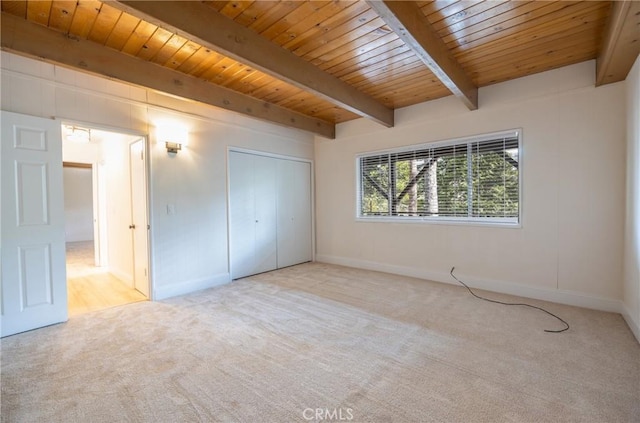 unfurnished bedroom with light colored carpet, beam ceiling, and wooden ceiling