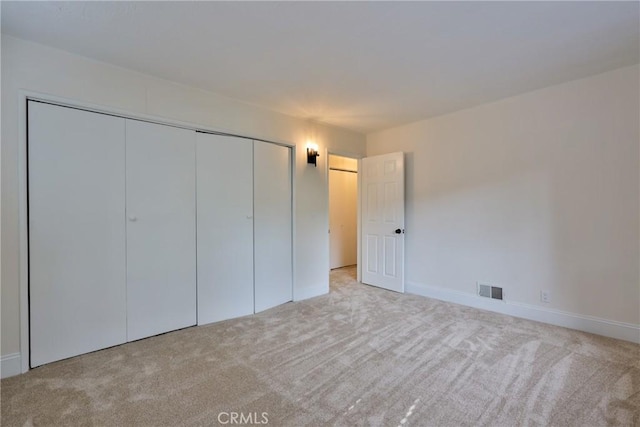 unfurnished bedroom featuring light colored carpet and a closet