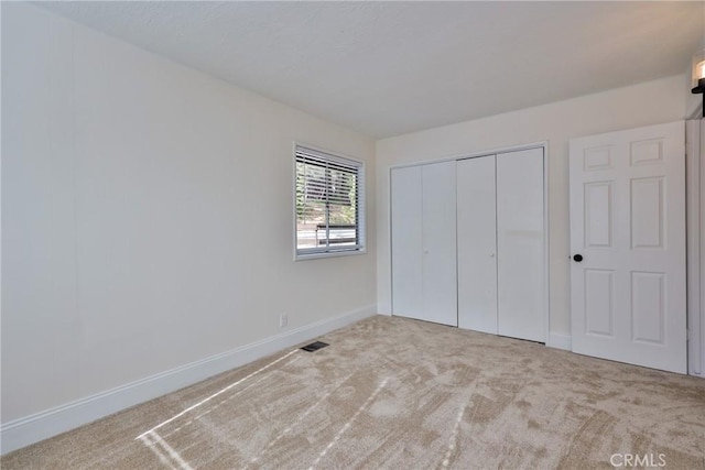 unfurnished bedroom featuring light colored carpet and a closet