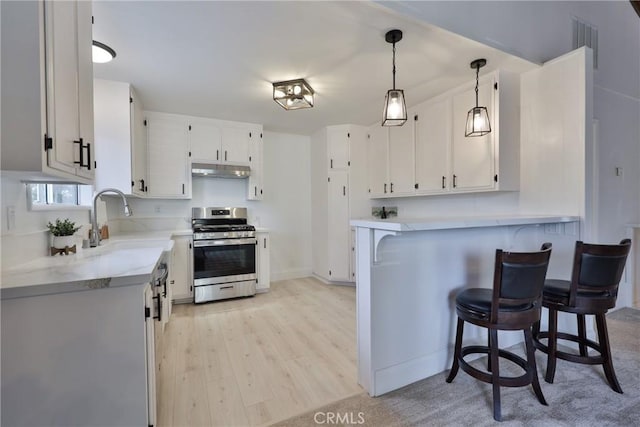 kitchen with white cabinetry, stainless steel range oven, a kitchen breakfast bar, and decorative light fixtures