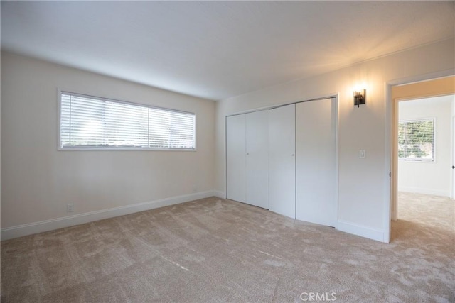 unfurnished bedroom with light colored carpet and a closet