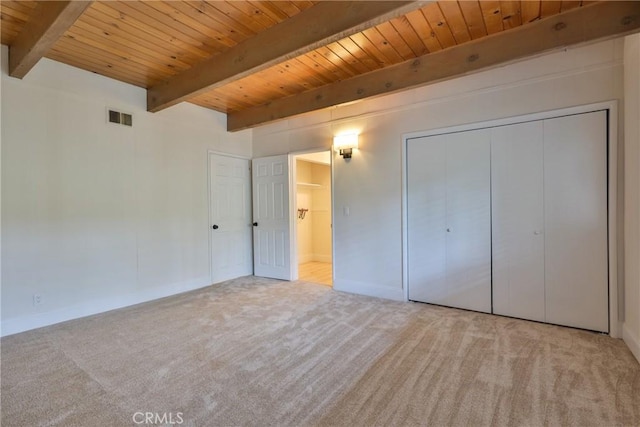 unfurnished bedroom with wood ceiling, light colored carpet, beam ceiling, and a closet