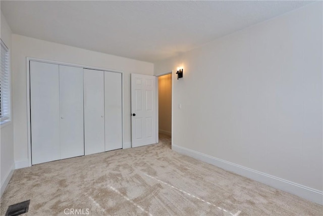 unfurnished bedroom with light colored carpet and a closet