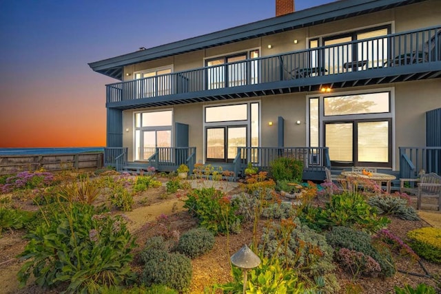 back house at dusk featuring a balcony