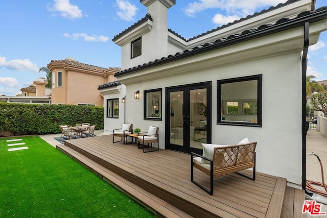 back of house with a wooden deck, a yard, and french doors