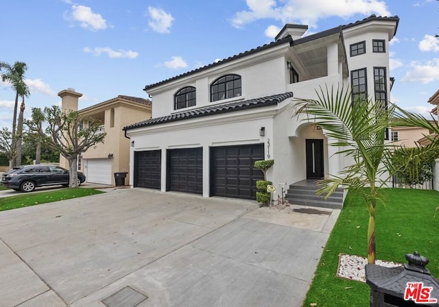 mediterranean / spanish-style home featuring a garage and a front lawn