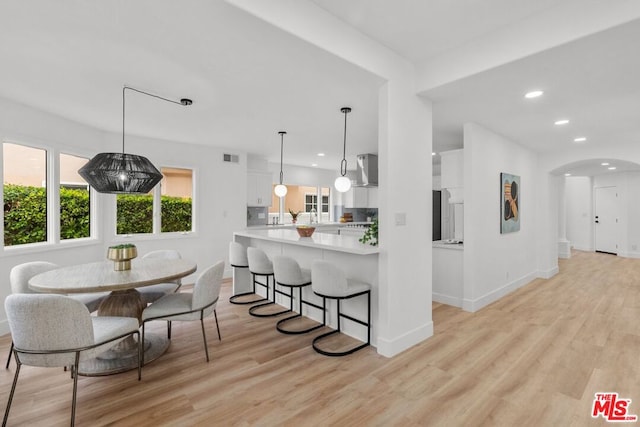 kitchen featuring white cabinetry, pendant lighting, light hardwood / wood-style floors, and kitchen peninsula