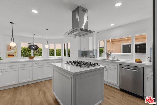 kitchen with sink, island range hood, white cabinets, and appliances with stainless steel finishes