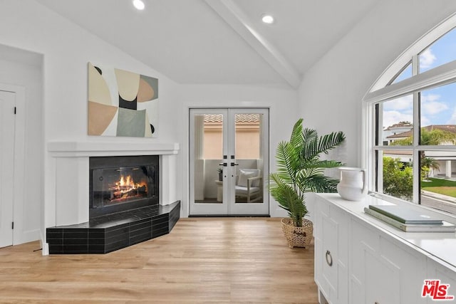 interior space featuring a fireplace, vaulted ceiling, light hardwood / wood-style floors, and french doors