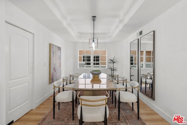 dining room with hardwood / wood-style flooring and a tray ceiling