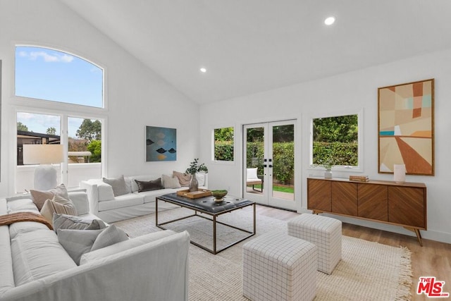 living room with high vaulted ceiling, french doors, and light wood-type flooring