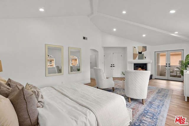 bedroom featuring beam ceiling, high vaulted ceiling, light wood-type flooring, and french doors