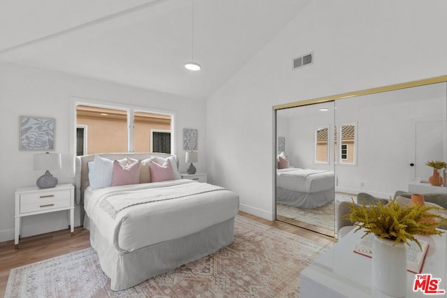 bedroom featuring high vaulted ceiling, light hardwood / wood-style floors, and a closet