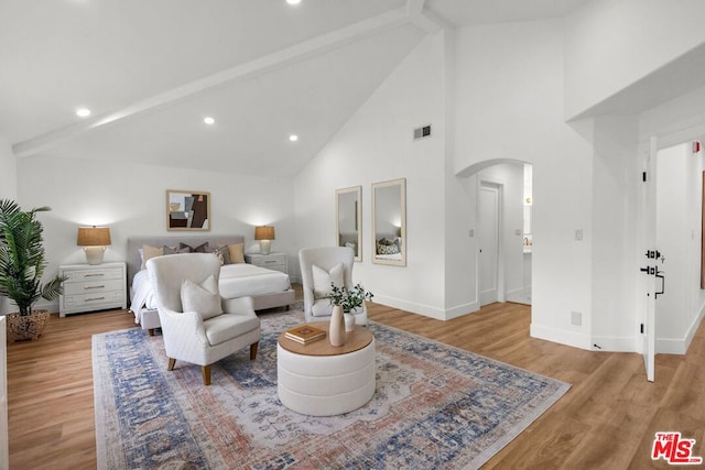 bedroom with beam ceiling, high vaulted ceiling, and light hardwood / wood-style flooring