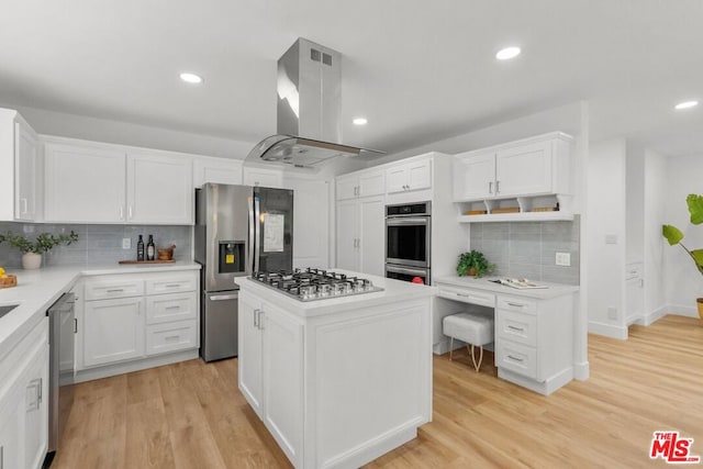 kitchen featuring appliances with stainless steel finishes, white cabinets, island exhaust hood, a center island, and light hardwood / wood-style flooring