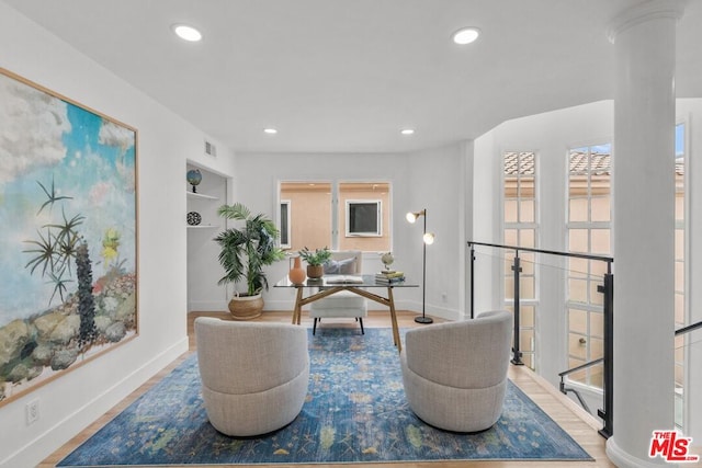 interior space with ornate columns, hardwood / wood-style floors, and built in shelves