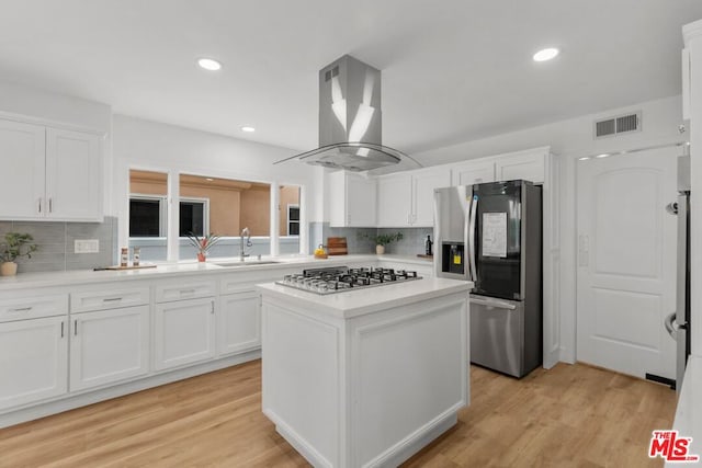 kitchen featuring sink, white cabinetry, stainless steel appliances, island exhaust hood, and a kitchen island