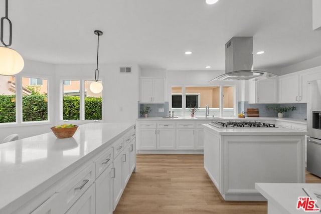 kitchen featuring white cabinetry, island exhaust hood, hanging light fixtures, and a center island