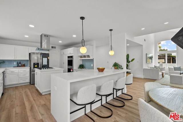 kitchen featuring a kitchen island, pendant lighting, white cabinetry, island exhaust hood, and light hardwood / wood-style flooring