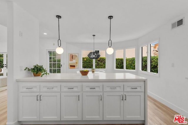 kitchen with white cabinetry, light hardwood / wood-style floors, and hanging light fixtures