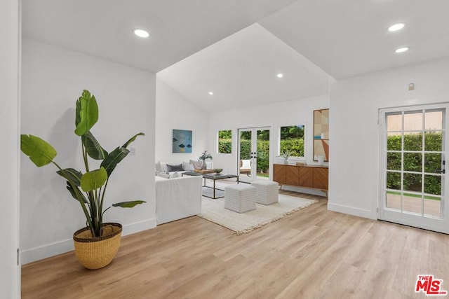 living room with lofted ceiling, light hardwood / wood-style floors, and french doors