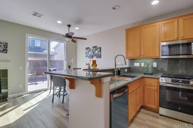 kitchen with stainless steel appliances, sink, backsplash, and kitchen peninsula