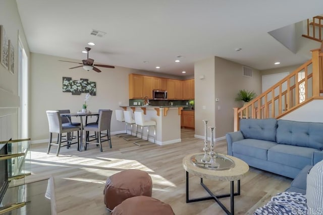 living room featuring light hardwood / wood-style flooring and ceiling fan