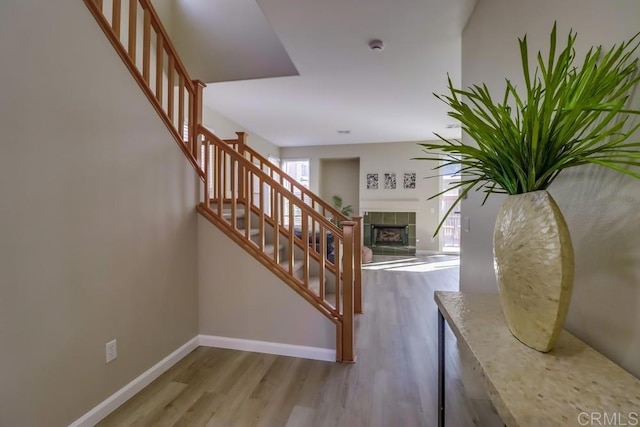 stairway featuring a tiled fireplace and hardwood / wood-style flooring