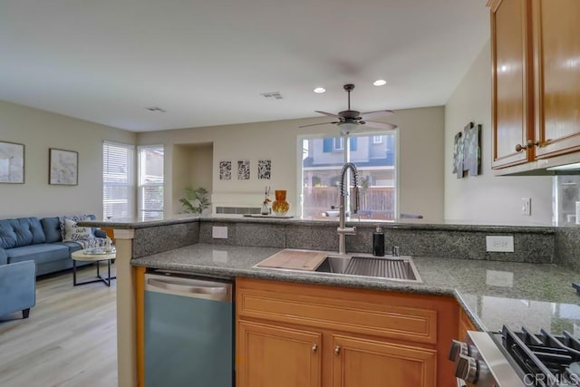 kitchen with sink, stone countertops, ceiling fan, stainless steel appliances, and light hardwood / wood-style floors