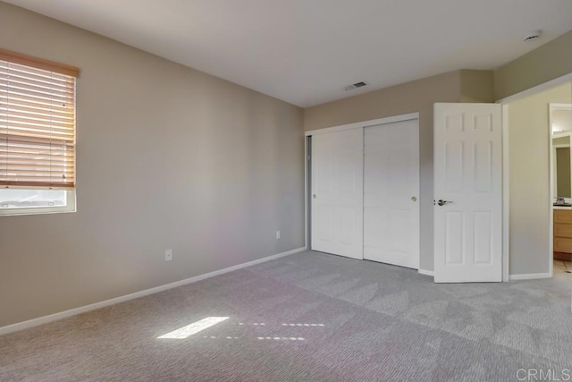 unfurnished bedroom with light colored carpet and a closet