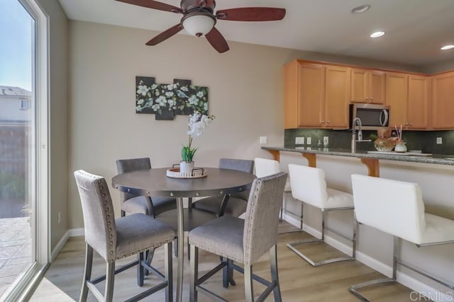 kitchen featuring tasteful backsplash, light stone countertops, light hardwood / wood-style floors, and kitchen peninsula