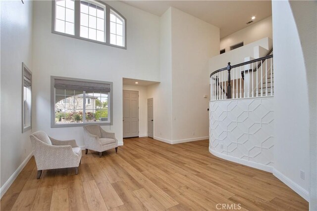 unfurnished room featuring a towering ceiling and light wood-type flooring