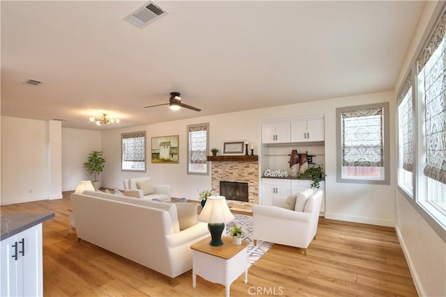 living room featuring a wealth of natural light, light wood-type flooring, a fireplace, and visible vents