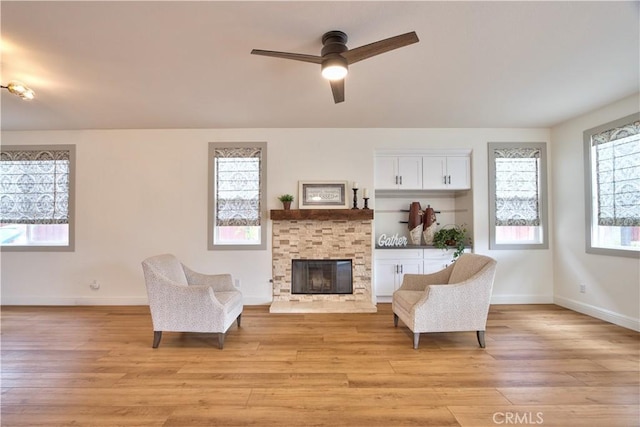 sitting room featuring ceiling fan, a fireplace, and light wood-type flooring